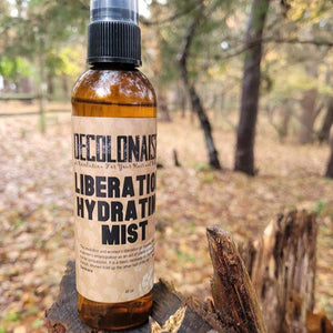 Liberation! Hydrating Mist 4 oz size on a tree stump in outdoor wooded area 